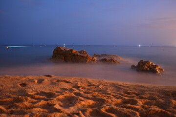 A rock on a spanish beach in dusk at a summer evening on mediterranean sea.