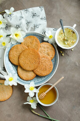Honey cookies with natural patterns on a plate on a dinner table with flowers and tea. Food photography in light colors with cookies and spring daffodils.