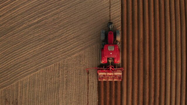 Top view of a red tractor seeding corn on agriculture field. Start of the planting season. March 2021, Dnepro, Ukraine. 