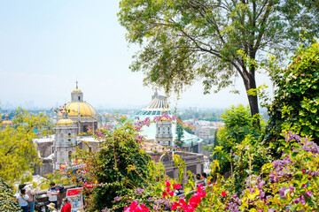 Mexico City, Mexico; april 24 2022: ancient and modern guadalupe basilica behind trees and flowers.