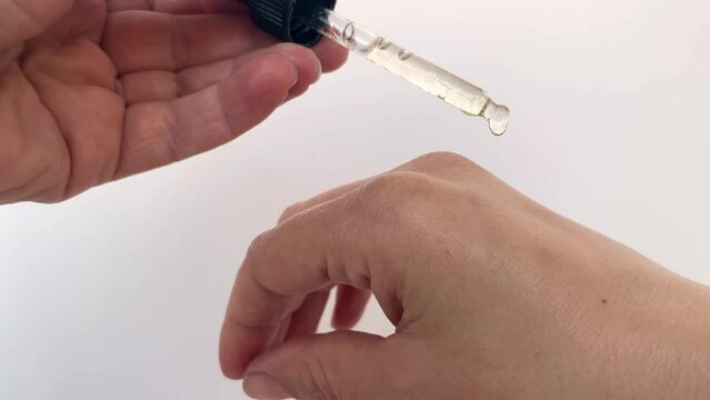 Close-up of women's hands holding a cone with cosmetic oil for the body and hands, a drop of oil dripping onto the skin.