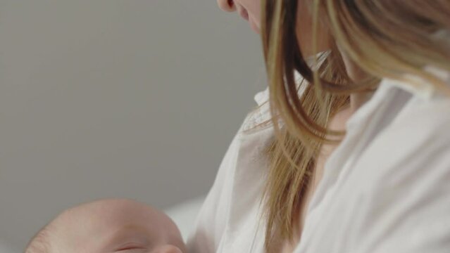 Newborn baby son sleeping in tender mother's embrace