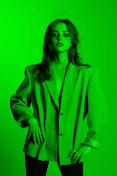 High-fashion. Young Beautiful Woman With Wavy Hair In Green Neon Light. Sexy Girl In A Jacket. Creative Colorful Fashion Portrait Generation Z