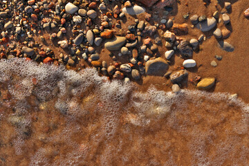 Directly Above Flatlay of Gentle Waves Lapping Sand and Pebble Beach with Pristine Clear Cool Water 