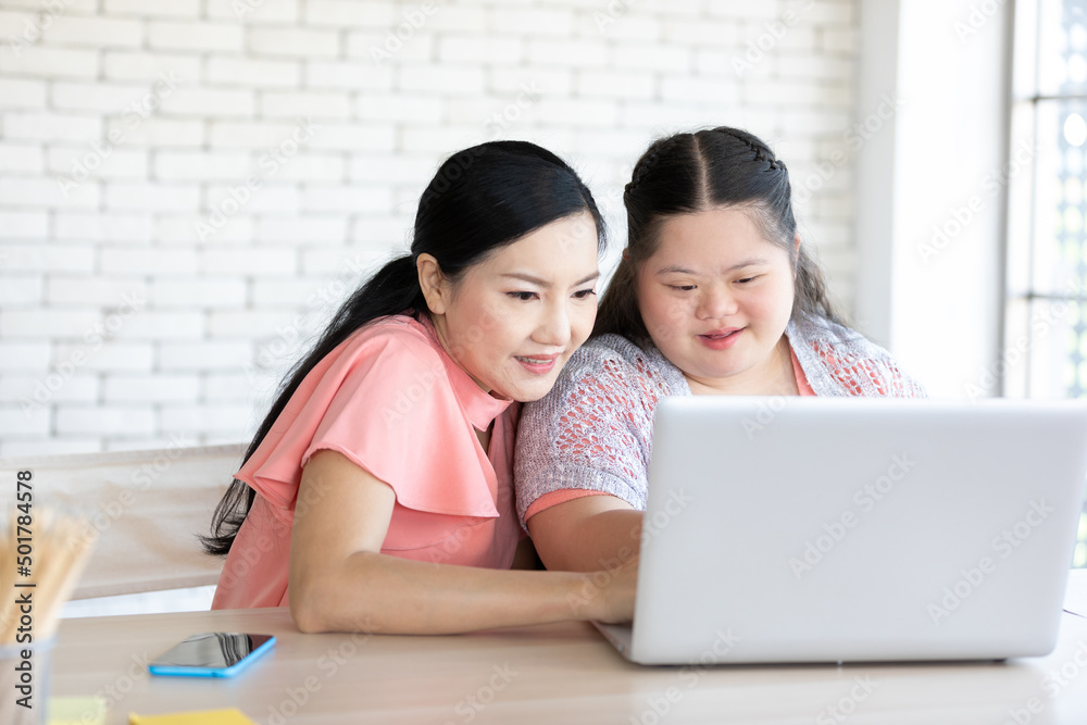 Wall mural down syndrome teenage girl and her teacher using laptop computer together on a table