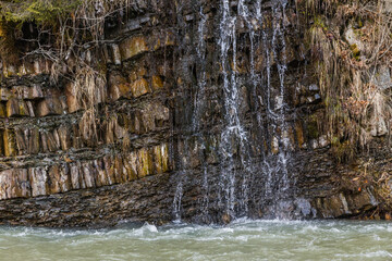 Mountain creek and wooden roots on hill with stones.