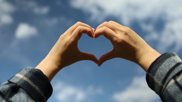 Girl hand heart shaped love blue sky