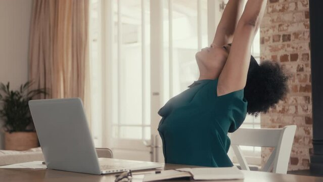 4k video footage of a businesswoman stretching while using a laptop