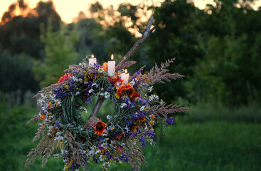 Flower wreath with burn candles on evening meadow. Summer Solstice Day, Midsummer concept. floral...