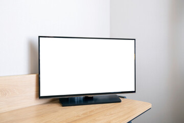 Blank white screen of LED TV as mockup on a desk, space for text