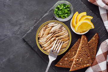 canned sprats in oil on a dark stone background