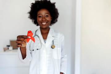 Female doctor with red ribbon. Cancer concept. Doctor Holds Red Ribbon to awareness world aids day Dec. 1. AID, HIV red ribbon. Symbol of awareness, charity, support in disease, illness. - obrazy, fototapety, plakaty