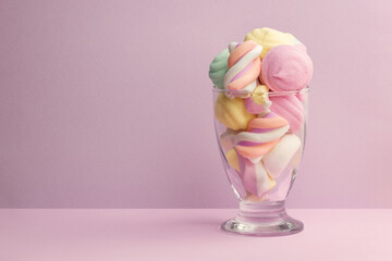 Cocktail glass full of colorful marshmallows. Isolated glass full of candies and sweets with pastel...