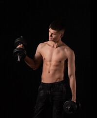 Fototapeta na wymiar Portrait of a muscular man lifting weights against a dark background