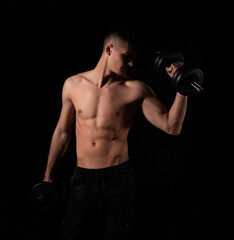 Fototapeta na wymiar strong sexy man with dumbbells on a black background