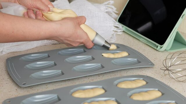 Making madeleine cookies. Person is dividing batter evenly among madeleine pan