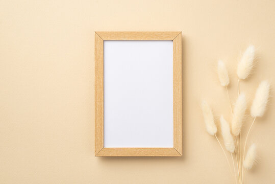 Business concept. Top view photo of wooden photo frame and white lagurus flowers on isolated beige background with copyspace