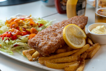 Plate with tasty fried fish, chips and sauces on table