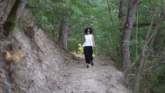 Hiker woman walking on path in summer fores