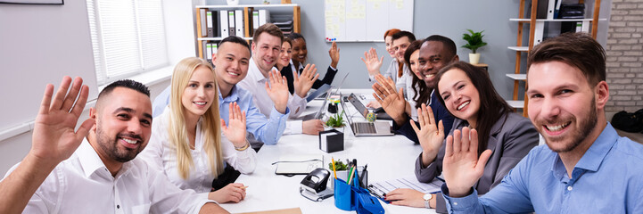 Happy Group Of Businesspeople Waving Hands In Office