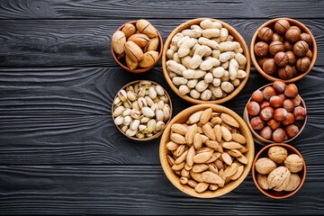 set of different nuts on a black rustic wooden background