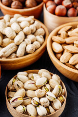 set of different nuts on a black rustic wooden background