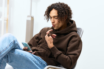 Fototapeta premium portrait of a man sitting on a chair with a phone communication interior light background