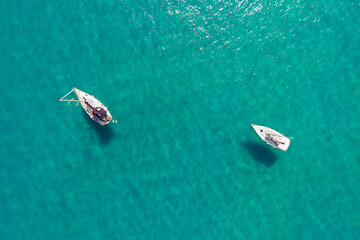 mare smeraldo con 2 barche bianche, ripreso dall'alto.
