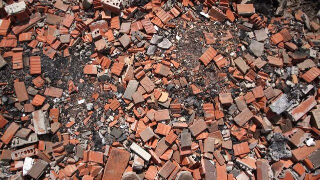Point of view 4k video footage of man standing among many broken damaged red bricks and rubbles laying on black burnt out ground. Remains of ruined house. Causes of war 2022 of Russia against Ukraine