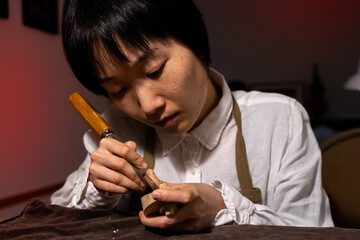 young Chinese female violin maker working with gouge to making a new violin