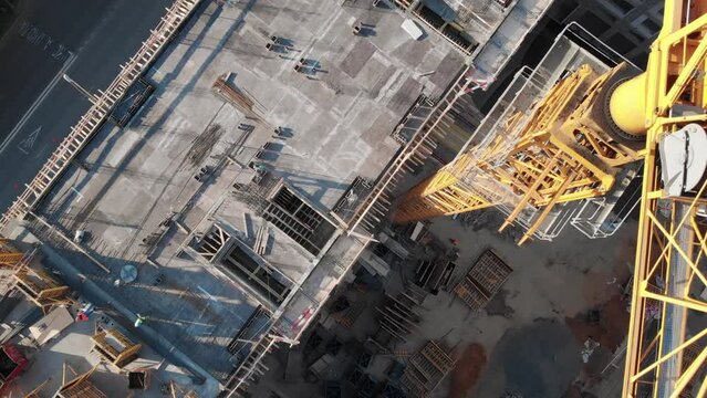 Top view to the construction works on the roof of a multi-storey building. Camera moves up along the giant crane showing all the construction site on the rooftop.