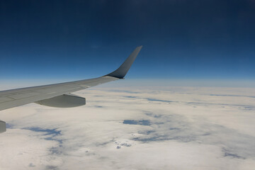 Obraz premium Flying traveling view from airplane window on the wing on clouds blue sky background