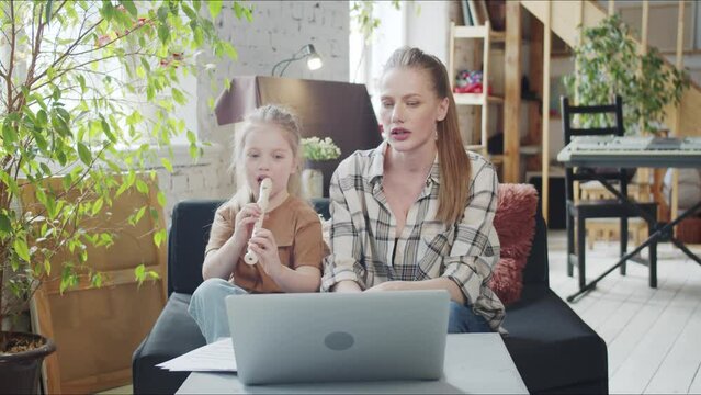 The girl, together with her mother, is engaged in a music tutor through a computer