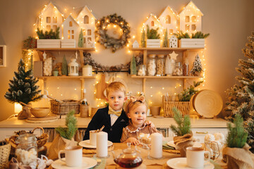 pretty little girl and boy at the kitchen table. christmas decor