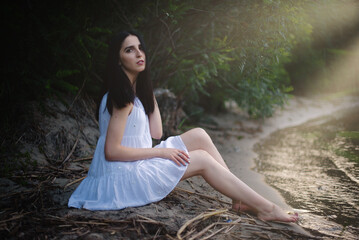 Beautiful sexy girl in a short white dress in nature near the river