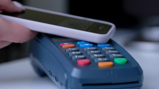 Woman using NFC technology for paying in the shop or cafe. Girl phone payment.
