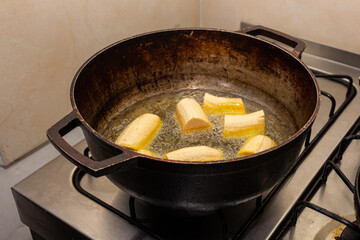 green banana frying in a pan with oil