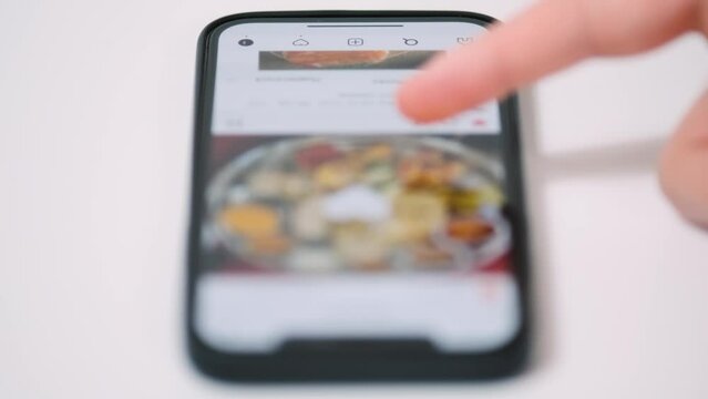 Finger swipe photos of food in the social network application. Internet surf on the phone. Scrolling through photos on phone