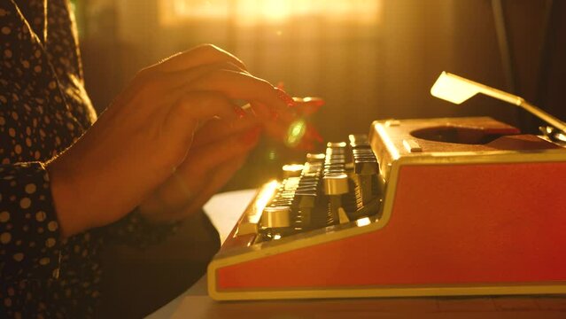 Typing text on old retro typewriter. Adult woman hands press keyboard keys. Storytelling and creative on office desk in sunset time. Confidential information, censorship in media