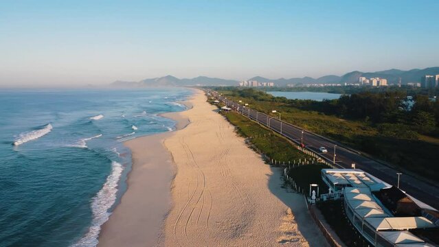 Aerial view of Reserva beach, Marapendi lagoon and car traffic on Lucio Costa avenue. Barra da Tijuca and Recreio, in Rio de Janeiro, Brazil. Sunrise. Sunny day. Drone take. Praia da Reserva.