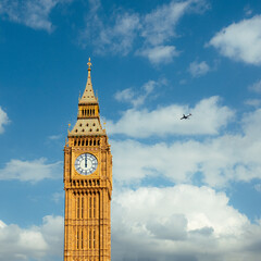 Plane flying over big Ben with blue skies 