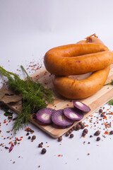 Classic boiled meat pork sausages on chopping board with pepper and basil and cherry tomatoes on wooden background. Snack for kids