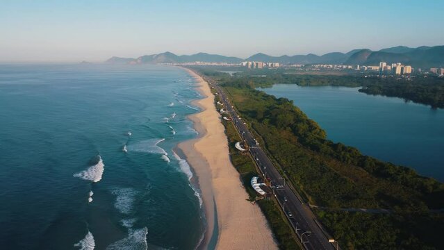 Aerial view of Reserva beach, Marapendi lagoon and car traffic on Lucio Costa avenue. Barra da Tijuca and Recreio, in Rio de Janeiro, Brazil. Sunrise. Sunny day. Drone take. Praia da Reserva.