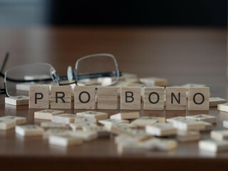 pro bono word or concept represented by wooden letter tiles on a wooden table with glasses and a...