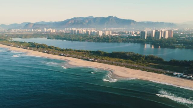 Aerial view of Reserva beach, Marapendi lagoon and car traffic on Lucio Costa avenue. Barra da Tijuca and Recreio, in Rio de Janeiro, Brazil. Sunrise. Sunny day. Drone take. Praia da Reserva.