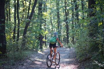 Fototapeta premium Rear view of active senior woman biker cycling outdoors in forest.