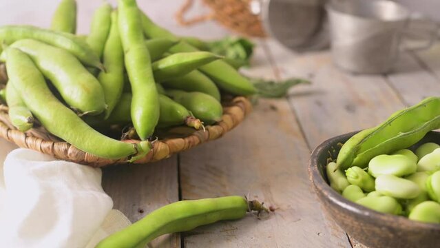 Fresh and raw green broad beans on wooden table.