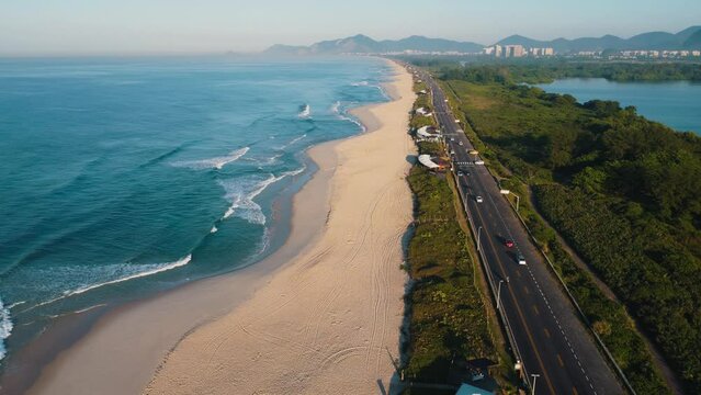 Aerial view of Reserva beach, Marapendi lagoon and car traffic on Lucio Costa avenue. Barra da Tijuca and Recreio, in Rio de Janeiro, Brazil. Sunrise. Sunny day. Drone take. Praia da Reserva.