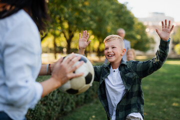 Happy little children with grandparents playing with ball outdoors in park