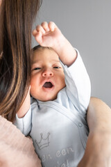 newborn baby boy in mother's arms with raised hand and open mouth